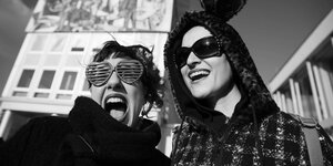 Zwei Demonstrantinnen mit Sonnenbrille und leopardiertem Plüschpullover bei einer Demo