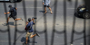 Demonstrant und ein Fotograf laufen vor der Polizei weg