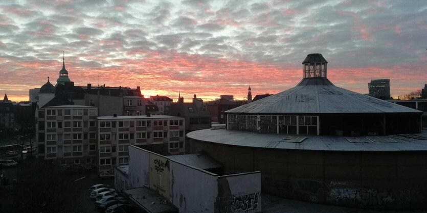 Rundbau mit Spitze vor Hamburg-Panorama mit rotem Himmel