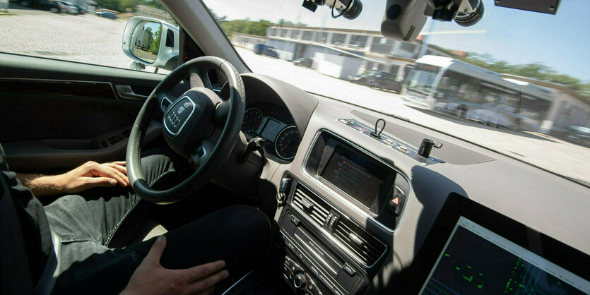 ein Mann sitzt im Auto auf dem Fahrersitz und hält die Hände auf den Beinen und nicht am Lenkrad