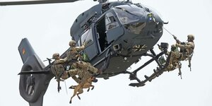 Soldaten hängen an einem fliegenden Bundeswehrhubschrauber