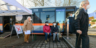 Rentner warten bei einem Testlauf vor einem Impfbus