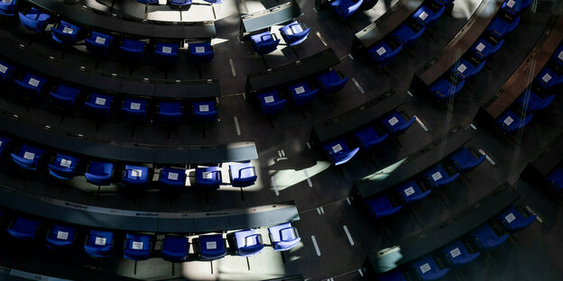 Ein Schattenspiel zeichnet sich im Plenum des Bundestags mit leeren Sitzen ab