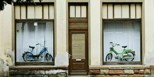 In einem Schaufenster stehen links und rechts je ein Mofa