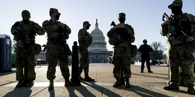 Uniformierte bewaffnete Männer stehen vor einem Gebäude