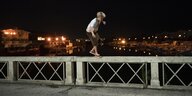 Fraser balanciert im Dunkeln auf dem Geländer einer Brücke