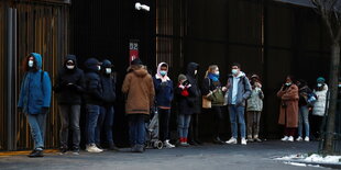 Studenten stehen mit Mund- Nasenschutz in einer Schlange