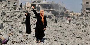 Eine palästinensische Frau hebt den Arm und ruft in einem zerstörten Wohngebiet im Gazastreifen
