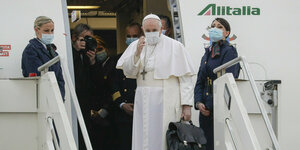 Papst Franziskus beim Einstieg in ein Flugzeug, in der Hand eine Aktentasche