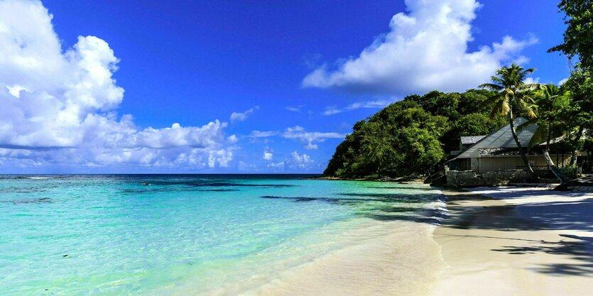 Postkartenidylle mit strahlend blauen Himmel und türkisfarbenden Wasser am Strand Long Bay Beach in Barbados