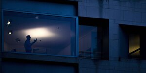 Die Silhouette eines Mannes zeichnet sich in einem Fenster ab