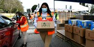 Eine Helferin trägt Kisten mit Lebensmitteln zu Bedürftigen