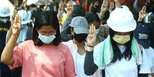 Anti-Putsch-Demonstranten zeigen das dreifingrige Symbol des Widerstandes und verbeugen sich im Gedenken