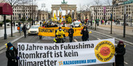 Menschen stehen hinter einem Transparent, im Hintergrund das Brandenburger Tor