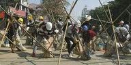 Personen mit Bauarbeiterhelmen bauen an Sperren auf einer Straße