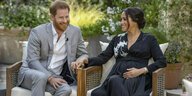 Ein Paar, Prinz Harry und Herzogin Meghan, sitzen auf Gartenmöbeln in eiem blühenden Garten