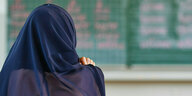 Eine Schülerin mit Kopftuch blickt auf die Tafel