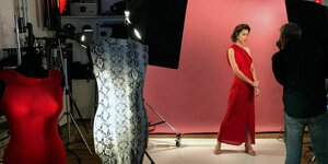 EIn Model posiert am Set im roten Kleid vor der Kamera