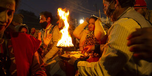 Menschenansammlung bei Nacht um ein zeremonielles Feuer herum