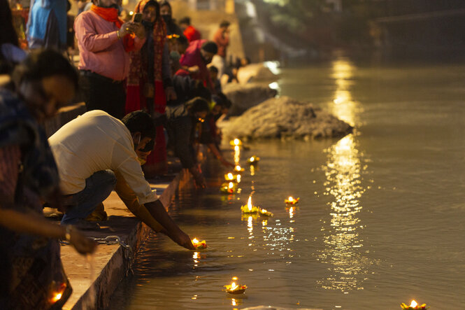 Menschen setzen bei Nacht kleine Körbe mit Flammen in den Ganges