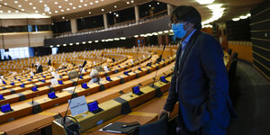 Der frühere katalanische Regionalpräsident Carles Puigdemont kommt zu einer Plenarsitzung des Europäischen Parlaments, er steht in einer Kabine und blickt auf das recht leere Plenum