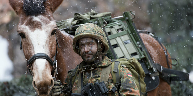 Ein Bundeswehrsoldat neben einem Pferd