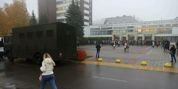 Menschen stehen vor dem Eingang einer Universität