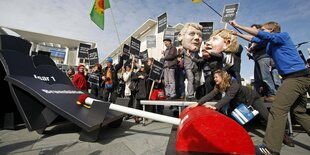 Anti - Atom Demo vor dem Kanzleramt mit Pappmache-Köpfen von Merkel und Röttgen . Mittels des großen Schalters schalten Bürger AKW ab, sie fallen wie Dominosteine um