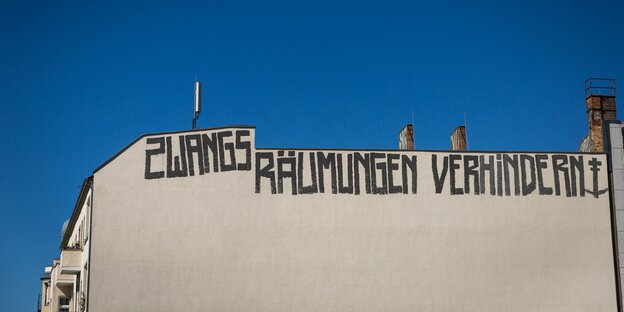 Graffiti "Zwangsräumungen verhindern" in Großbuchstaben an der Fassade eines Wohnhauses in Berlin