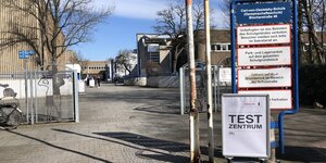 Vor dem unscheinbaren Schulgebäude weist ein Schild auf das Corona-Testzentrum