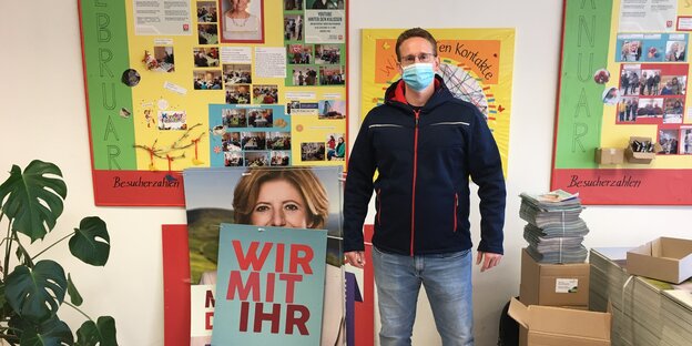 Ein Mann in Funktionsjacke steht vor einem Wahlplakat der SPD