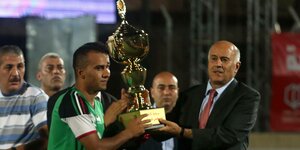 Präsident überreicht großen Pokal an Fußballer