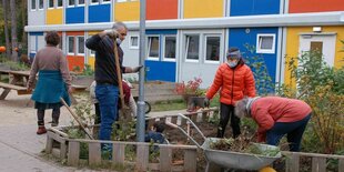 Menschen beim Gärtnern vor bunten Containerwohnungen