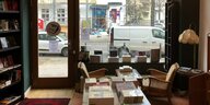 Blick aus einem Laden auf die Straße, Regale, Büchertisch und alte Sessel sind zu sehen.