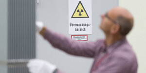 Ein Mann bei der Produktion von mit Uran angereicherte Brennstäbe - im Hintergrung das Zeichen für Radioaktivität