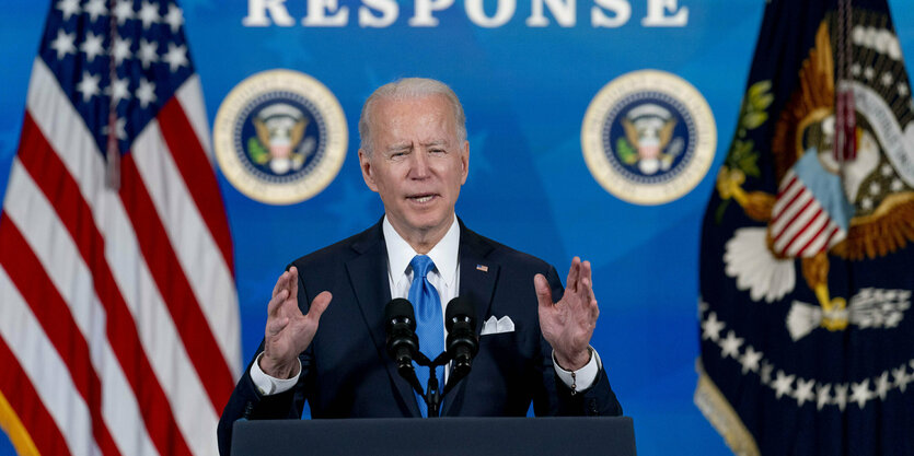 Joe Biden spricht an einem Rednerpult mit Flaggen im Hintergrund