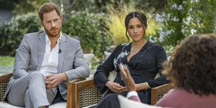 Prinz Harry und Herzogin Meghan auf Stühlen vor Buschwerk