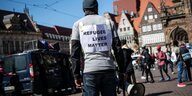 Ein Demonstrant steht mit einem Plakat mit der Aufschrift "Refugee lives matter" auf dem Bremer Marktplatz.