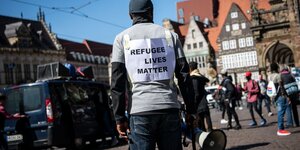 Ein Demonstrant steht mit einem Plakat mit der Aufschrift "Refugee lives matter" auf dem Bremer Marktplatz.