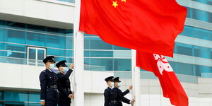 Polizisten hissen die chinesische Flagge und die Flagge von Honkong
