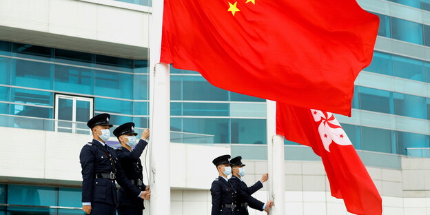 Polizisten hissen die chinesische Flagge und die Flagge von Honkong