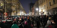 Menschen stehen auf einer dunklen Straße und verfolgen ein Konzert