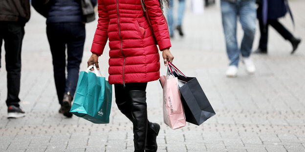 Eine Frau im roten Mantel mit Einkaufstüten