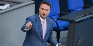 Mark Hauptmann steht im Bundestag hinter einem Pult und redet und gestikuliert