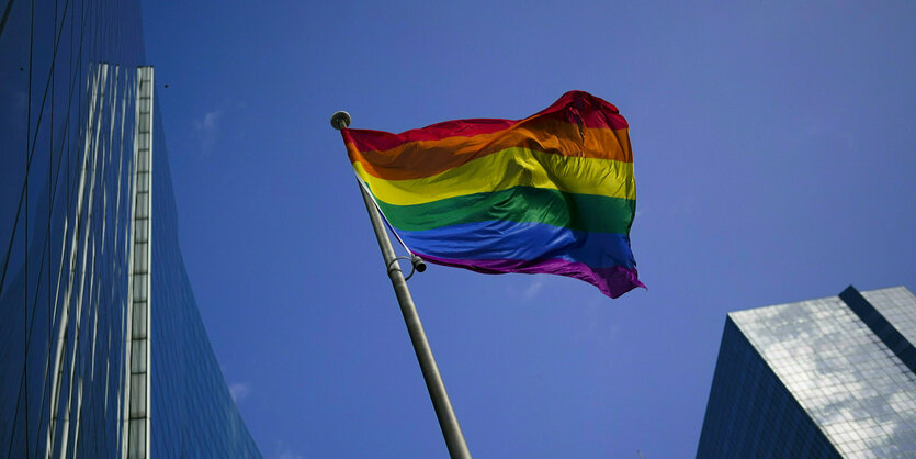 Regenbogenfahne flattert zwischen Hochhäusern