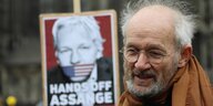 Ein Mann vor einem Fahrzeug, auf dessen Rückseite steht: "Australians bring Assange home"