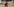 Eine Frau in einem pinkfarbene Kleid und Kopftuch geht eine Straße entlang