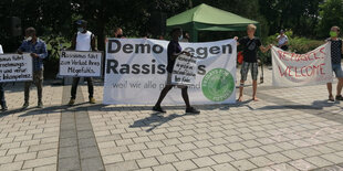 Ein Dutzend junge Leute mit Plakaten gegen Rassismus