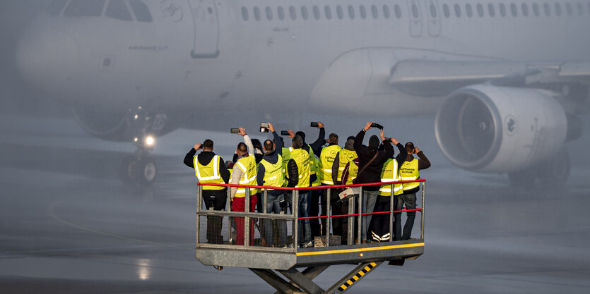 Menschen stehen auf einer Plattform und betrachten ein Flugzeug