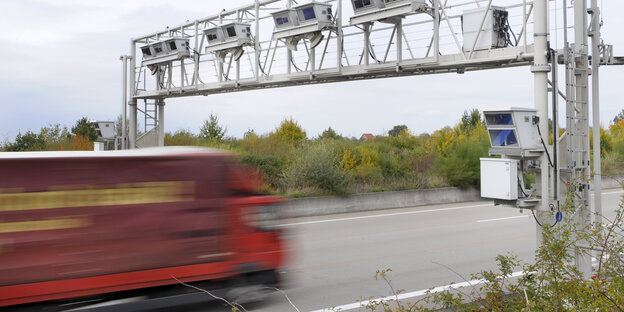 Lkw in Bewegungsunschärfe unterquert eine Mautbrücke